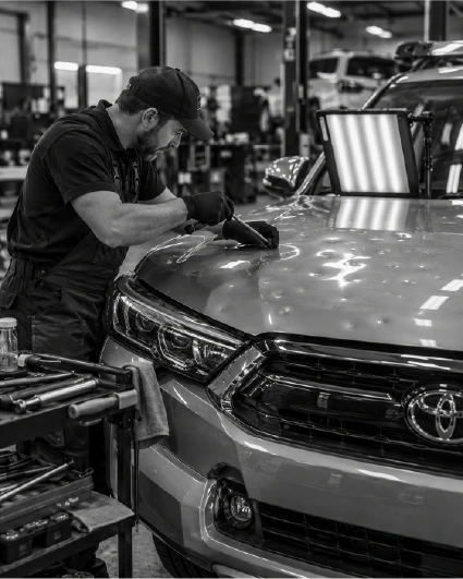 Hail-damaged car panel being repaired